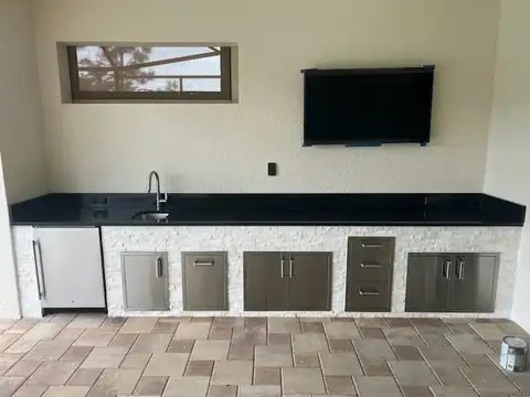 A linear outdoor kitchen with white stack stone installed in Naples, FL. A linear outdoor kitchen with white stack stone installed in Naples, FL.
