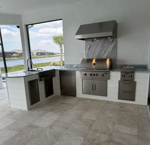 Custom outdoor kitchen with shiplap cladding featuring a grill and burners in Naples, FL Custom outdoor kitchen with shiplap cladding featuring a grill and burners in Naples, FL