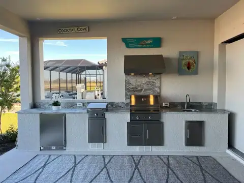 A straight custom outdoor kitchen in Naples, FL with Grill, Fridge, vent hood and sink. A straight custom outdoor kitchen in Naples, FL with Grill, Fridge, vent hood and sink.