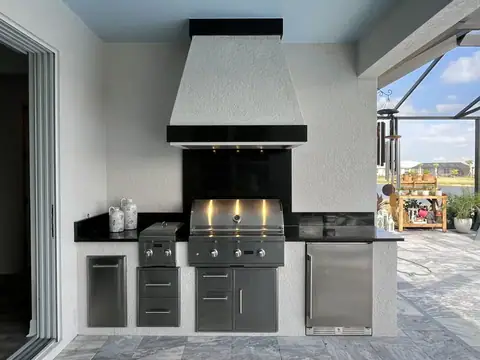 An outdoor kitchen with custom hood surround with granite bands done in Naples, FL. An outdoor kitchen with custom hood surround with granite bands done in Naples, FL.