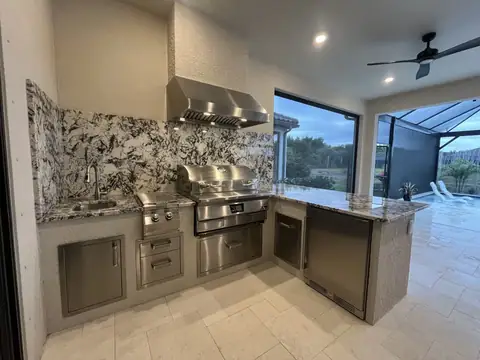 An outdoor kitchen with bar return and full height backsplash installed in Naples, FL. An outdoor kitchen with bar return and full height backsplash installed in Naples, FL.