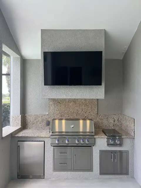 A custom outdoor kitchen with hood surround and mounted TV built in Naples, FL. A custom outdoor kitchen with hood surround and mounted TV built in Naples, FL.