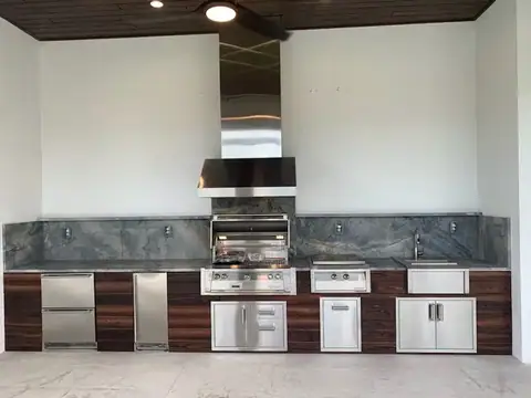 Beautiful custom outdoor kitchen faced with tongue and groove in Naples, FL. Beautiful custom outdoor kitchen faced with tongue and groove in Naples, FL featuring a grill, griddle drawer refrigerator and ice maker.