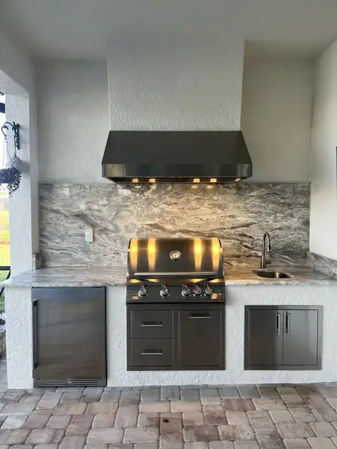 An outdoor kitchen with hood surround and full backsplash installed in Ft Myers, FL. An outdoor kitchen with hood surround and full backsplash installed in Ft Myers, FL.