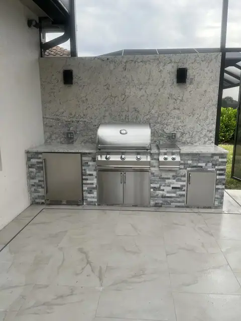 Outdoor kitchen with full granite rear wall and sconces built in Bonita Springs, FL. Outdoor kitchen with full granite rear wall and sconces built in Bonita Springs, FL.