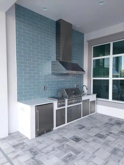 A custom outdoor kitchen with full tile backsplash built in Naples, FL. A custom outdoor kitchen with full tile backsplash built in Naples, FL with a Grill and burner.