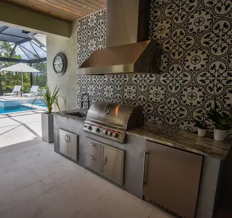An outdoor kitchen with ornate tile backsplash built in Punta Gorda, FL with ornate tile rear wall backsplash. An outdoor kitchen with ornate tile backsplash built in Punta Gorda, FL with ornate tile rear wall backsplash.
