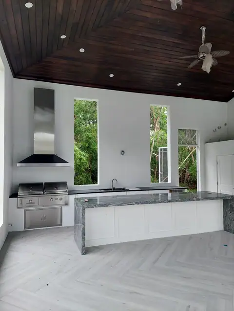 Large custom outdoor kitchen with dark tongue and groove ceiling in Naples FL. Large custom outdoor kitchen with dark tongue and groove ceiling in Naples FL with large grill and huge bar island.