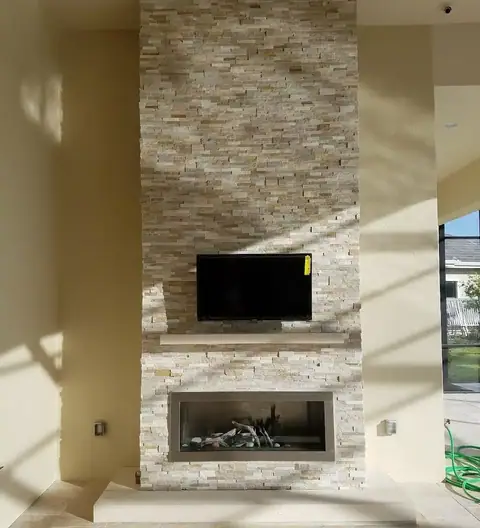 A full wall outdoor fireplace with stone a full stone surround with stucco hearth and mantle A full wall outdoor fireplace with stone a full stone surround with stucco hearth and mantle. Flush mounted TV above a natural gas fireplace insert.