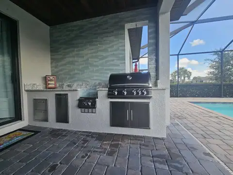 An outdoor kitchen with burner drop down and tile rear wall built in Naples, FL. An outdoor kitchen with burner drop down and tile rear wall built in Naples, FL.