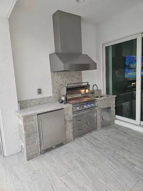 A custom outdoor kitchen with stack stone veneer built in Ft Myers, FL with a grill and outdoor fridge. A custom outdoor kitchen with stack stone veneer built in Ft Myers, FL with a grill and outdoor fridge.